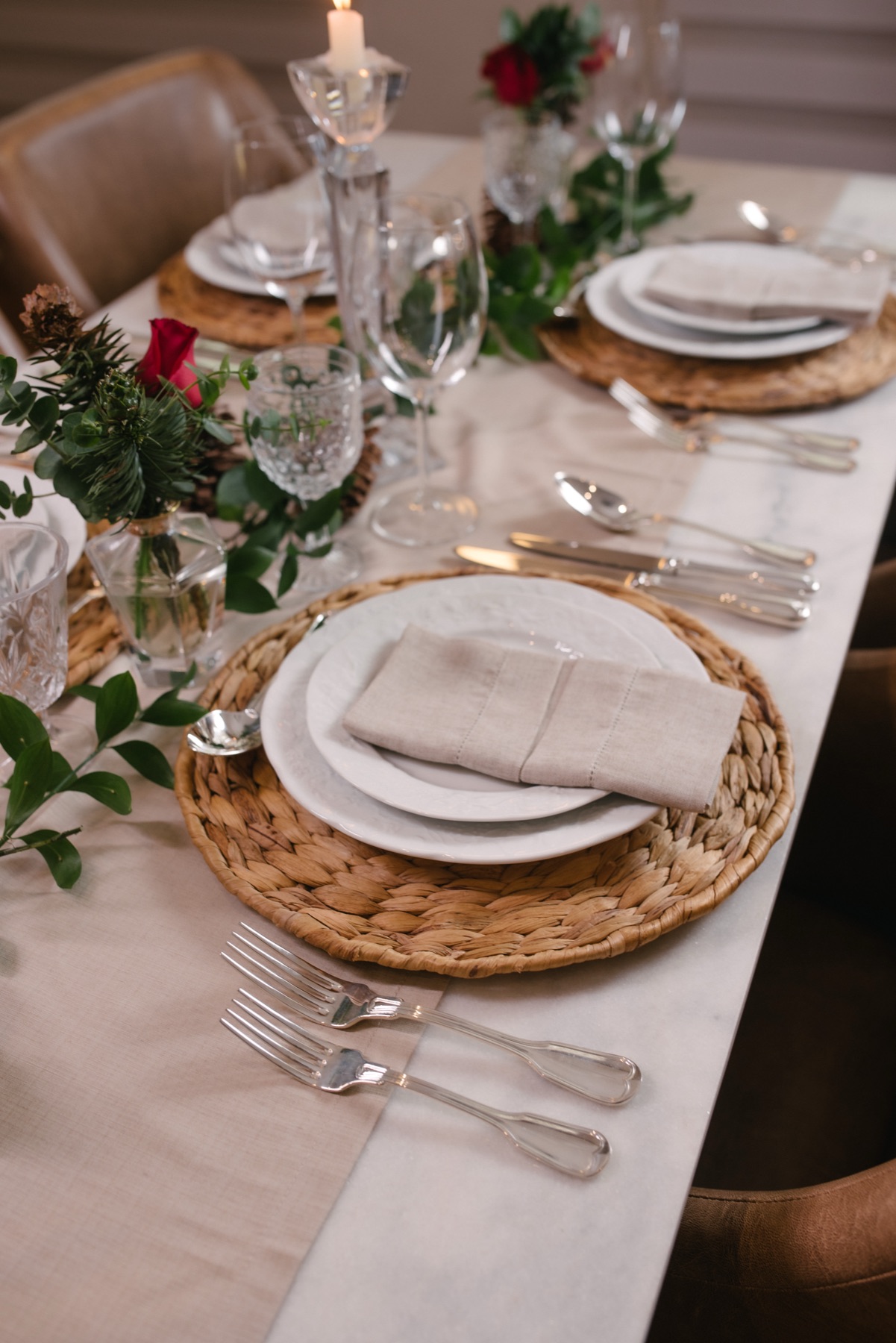 Mesa posta com sousplat de fibra natural, louça branca, guardanapo de linho e velas